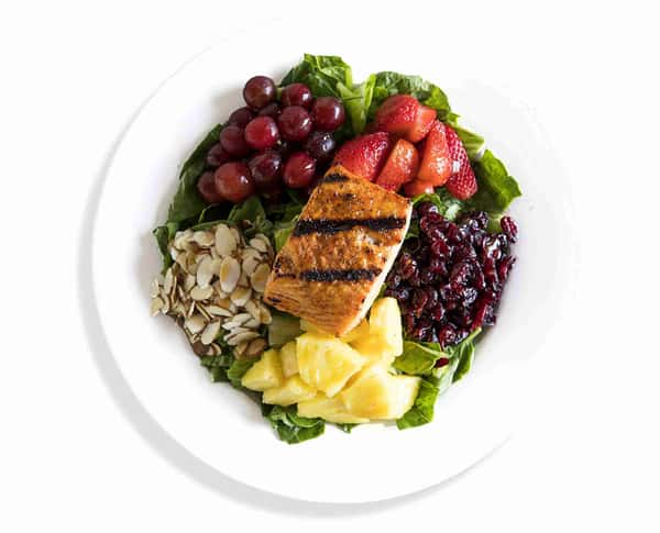 Overhead view of a fresh salmon bowl with greens and colorful toppings